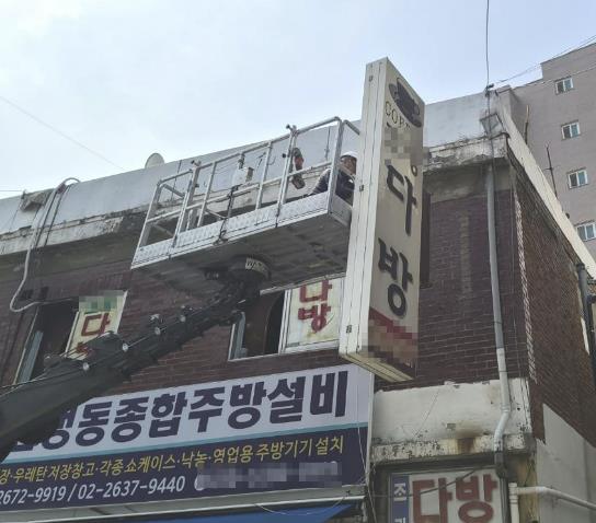 노후된 돌출간판을 철거하고 있는 모습